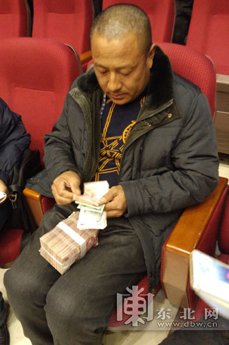 拿回分红,李洪军迫不及待地数起来.东北网记者 许俊鹏 摄